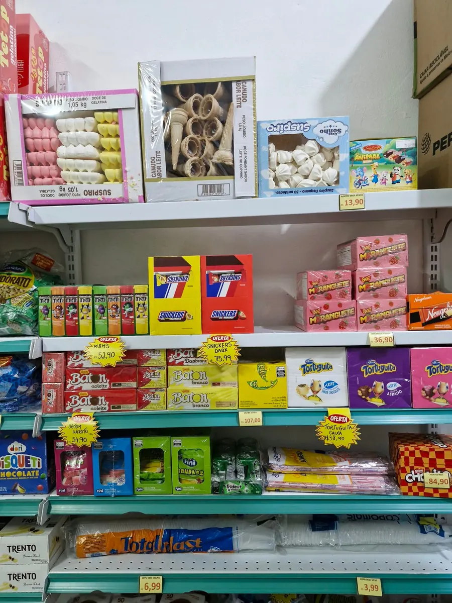 Prateleira com biscoitos, doces, chocolates e suspiros.