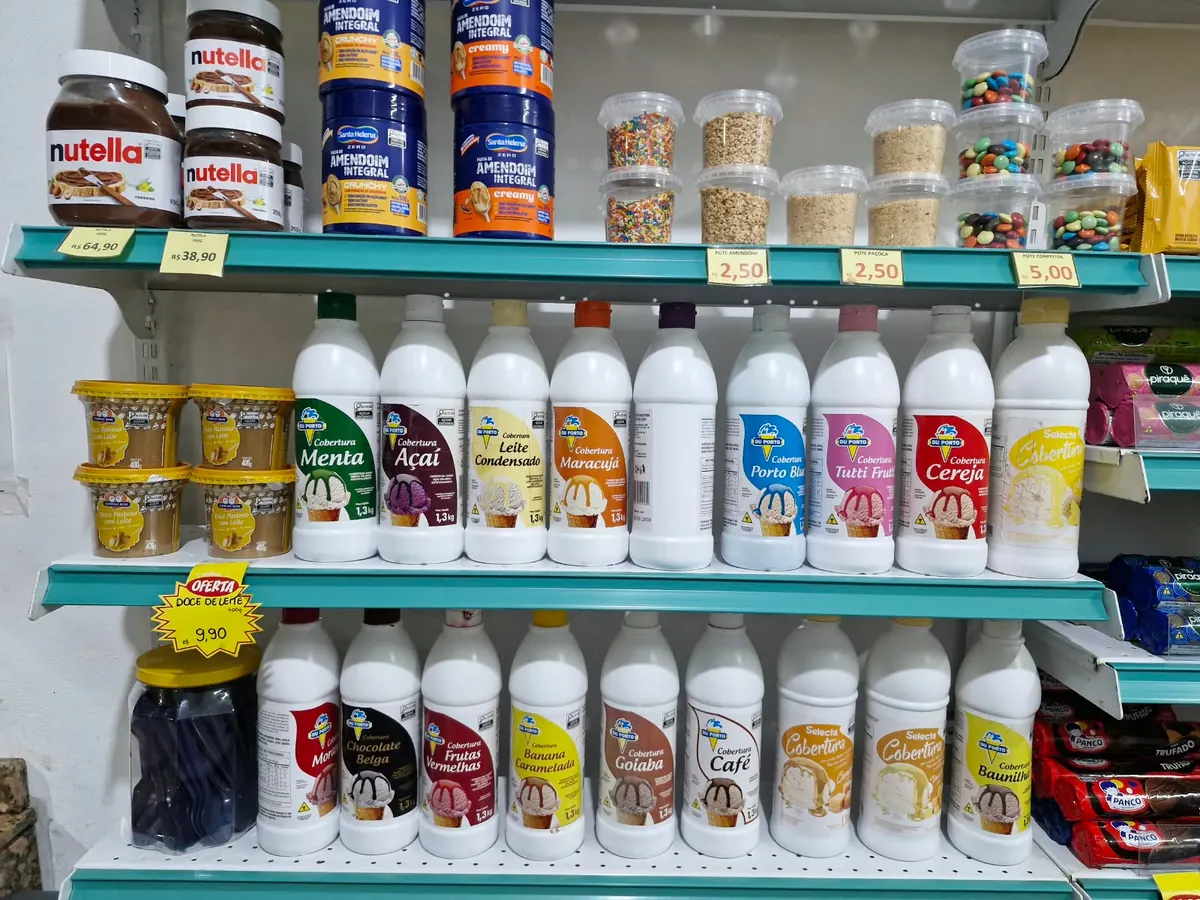 Prateleiras com caldas, confeitos e complementos para gelados.